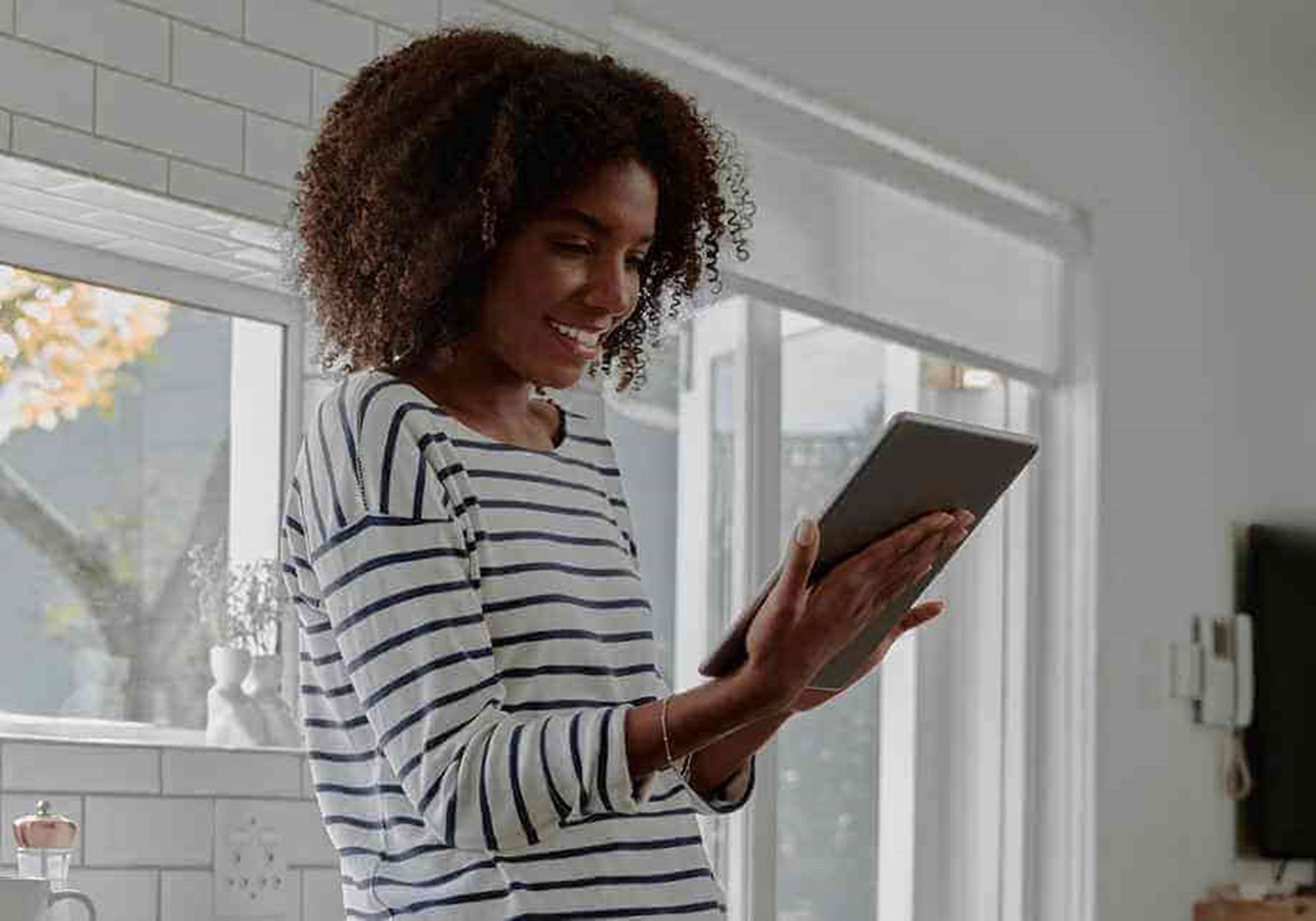 Woman In Stripe Shirt Reading On Digital Tablet In Kitchen