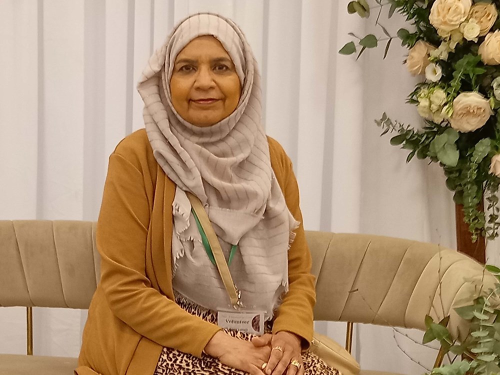 Picture of Rehana Ismail, a woman in a hijab sitting on a sofa smiling