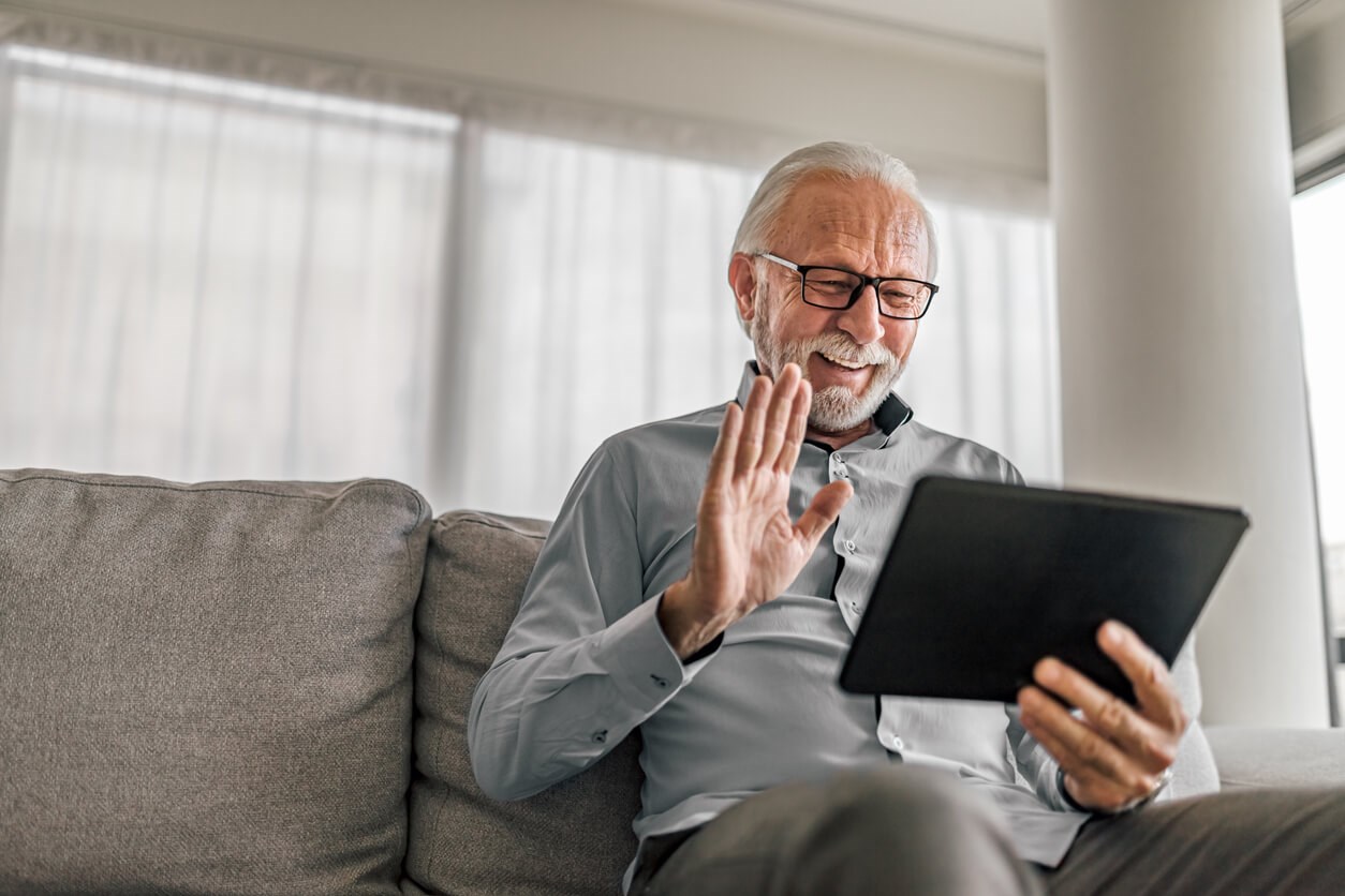 Man smiling and waving at device