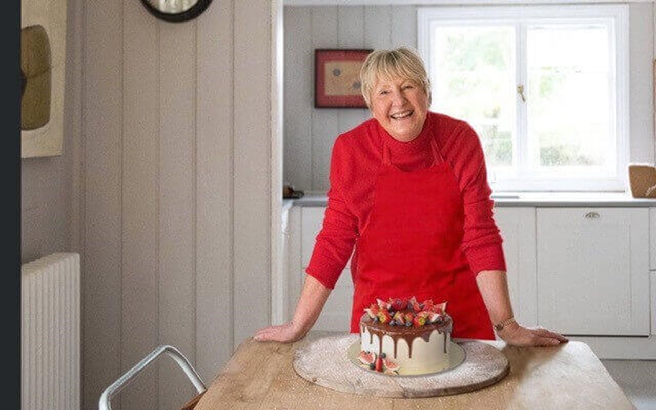 val stones stands behind a cake at a kitchen table
