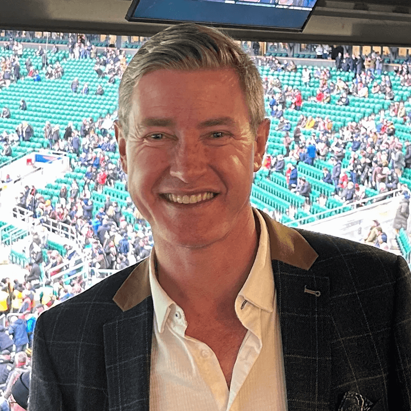 Picture of Andrew Gray, a man with grey hair smiling in a stadium