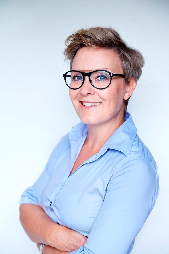 Picture of Mette Friberg Hitz, a woman with short brown hair in glasses and a blue shirt
