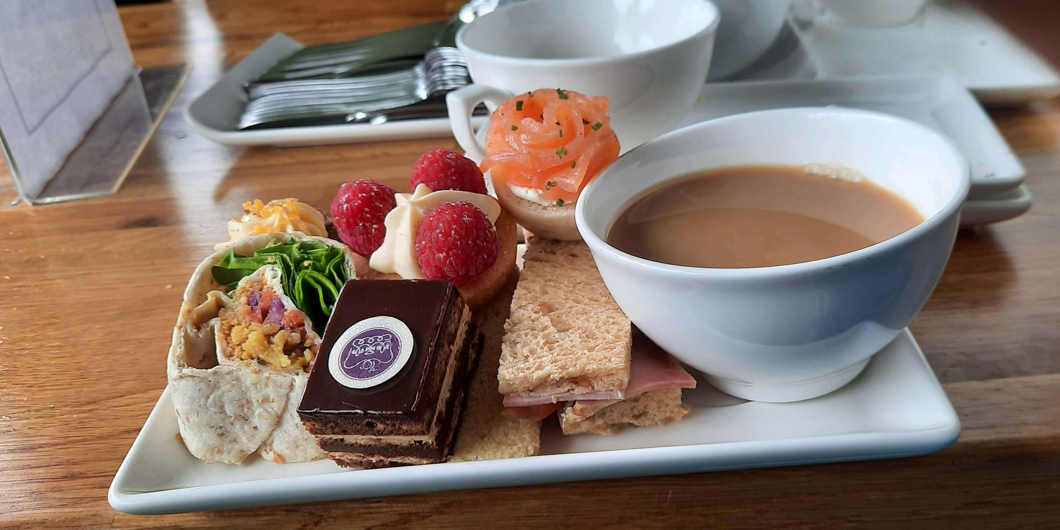 A plate of sandwiches and cakes and a cup of tea