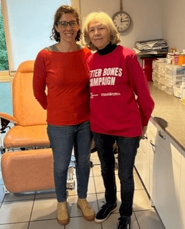 two ladies smile at the camera, one wearing a pink ROS sweatshirt