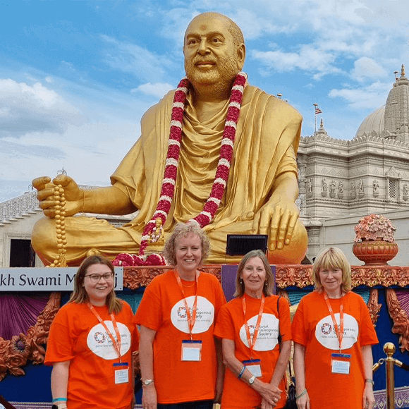 ROS staff and volunteers standing outside a golden statue of the creator of the Neasden Temple