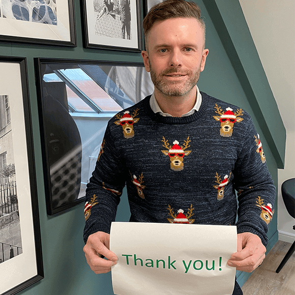 ROS CEO, Craig Jones, wearing a Christmas jumper and holding up a 'thank you' sign