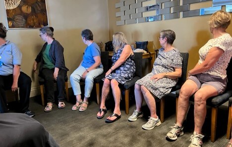 people sat on chairs facing away from the camera at an exercise class