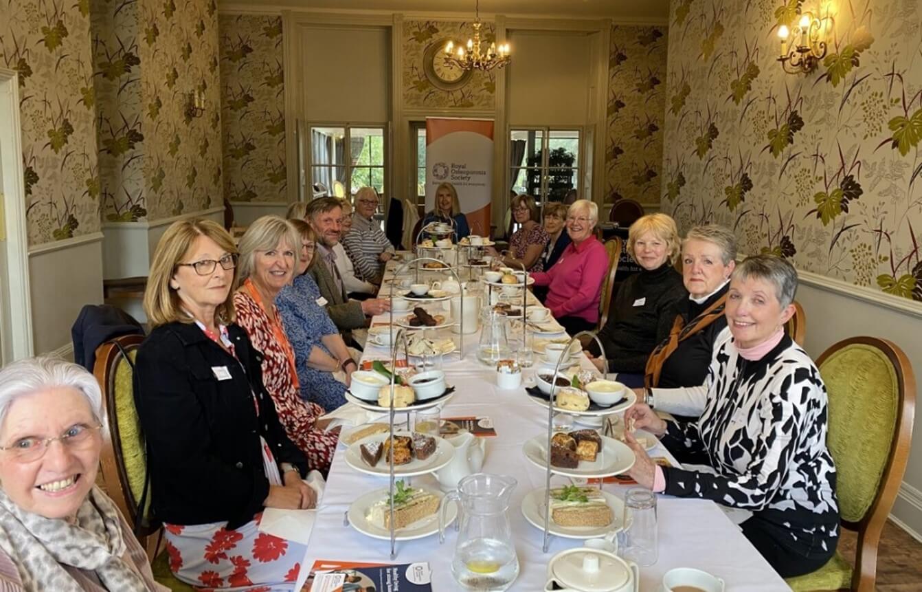 a group of people sit around a table covered in cakes