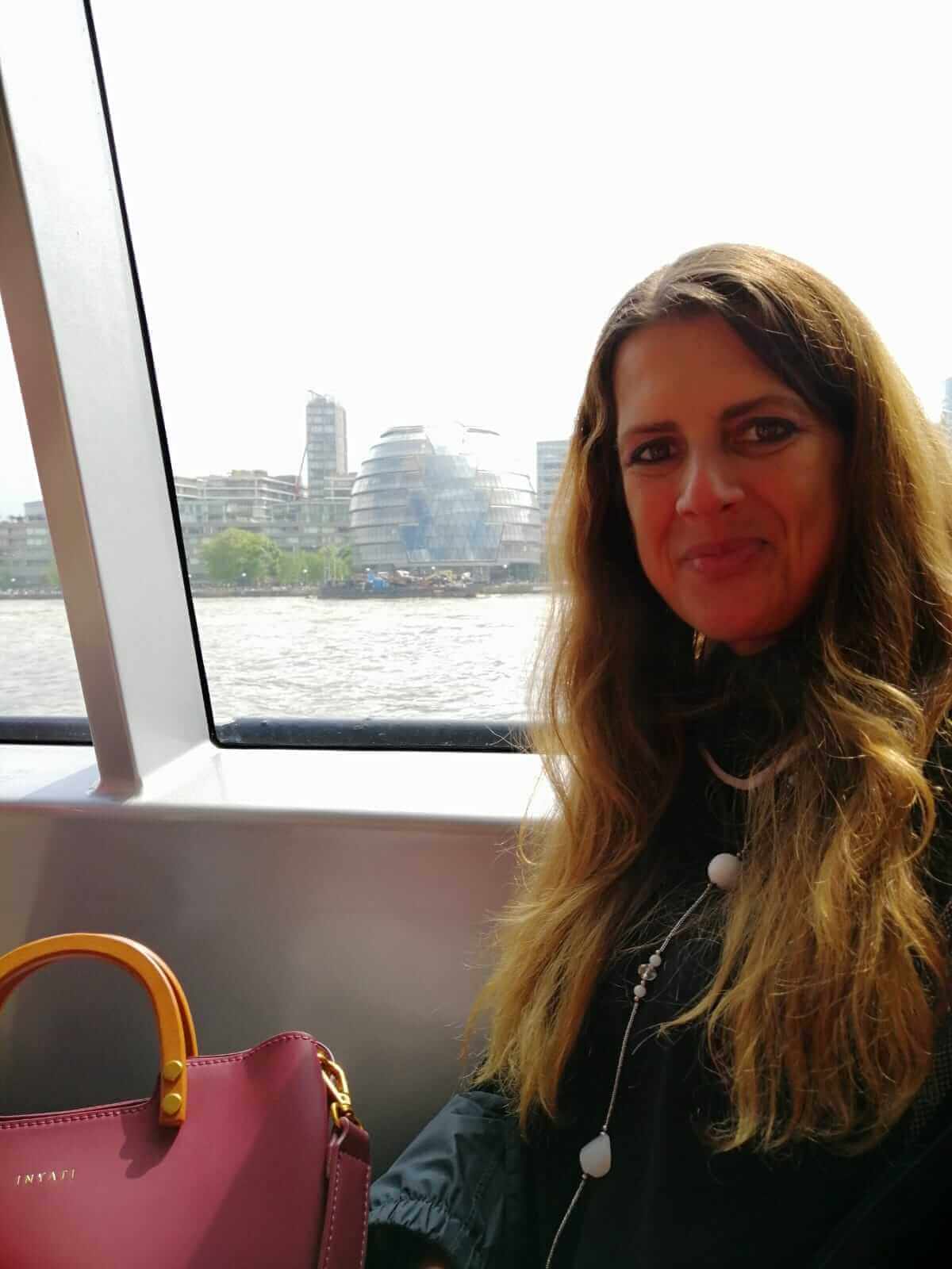 A woman sat smiling in a boat with a view of the river behind