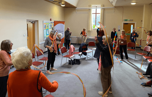 people in a room waving ribbons as part of an exercise class